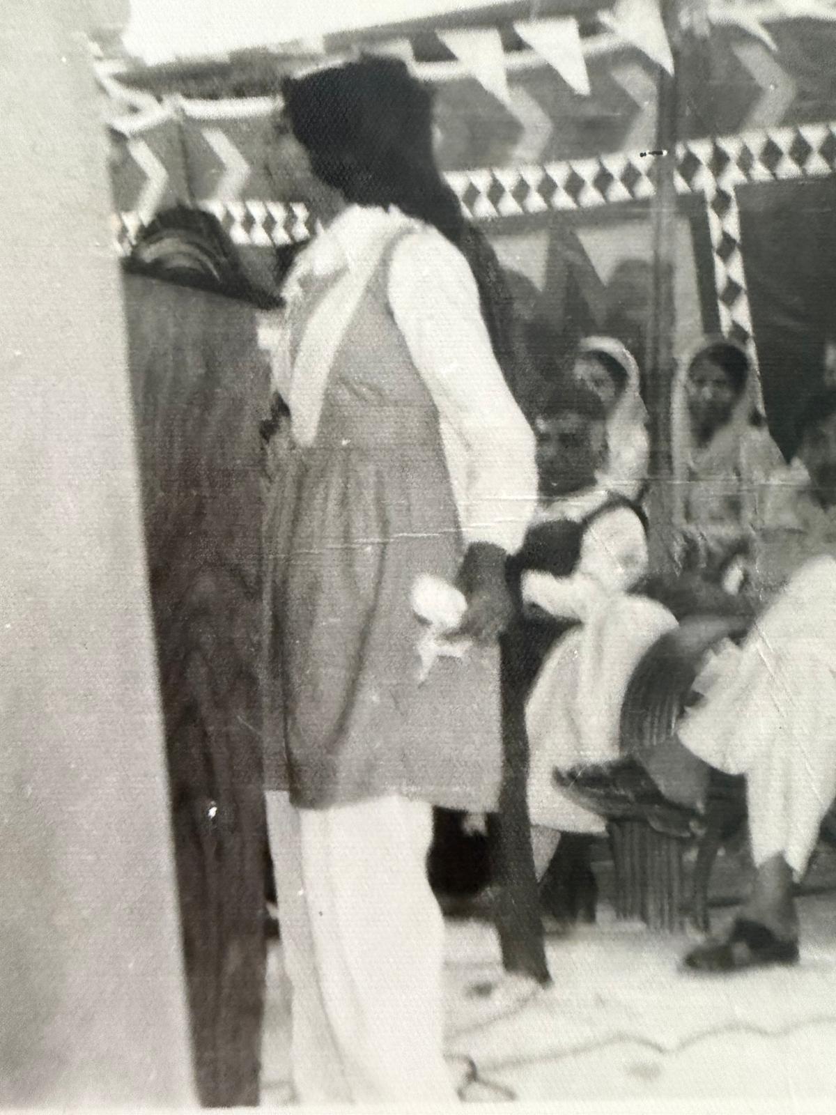 A speaker at a gathering under a decorated shamiana